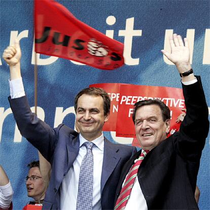 Zapatero saluda al público abrazado a Schröder en el cierre de campaña del Partido Socialdemócrata Alemán en Dortmund.