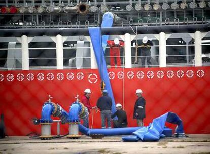 Varios operarios cargan de agua el primer barco con destino Barcelona.