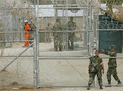 Un marino entra en el campo de Guantánamo mientras un detenido es llevado a su celda.