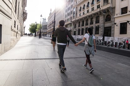 Una pareja pasea cogidos de la mano por las calles de Madrid.