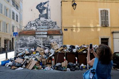 Una mujer realiza una fotografa de la basura acumulada en una esquina de una calle de Marsella (Francia) durante la huelga de basureros.