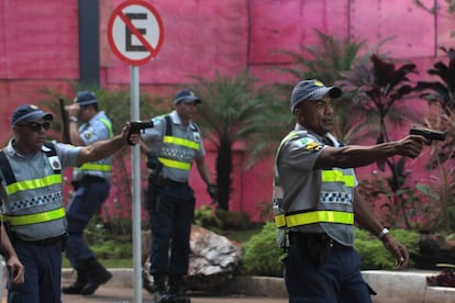 Policiais militares apontam armas de fogo contra manifestantes, diante da entrada do Ministério da Agricultura. 