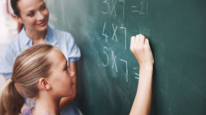 Una alumna completa una tarea bajo la mirada de su profesora.