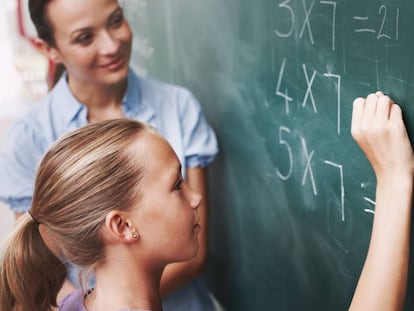 Una alumna completa una tarea bajo la mirada de su profesora.