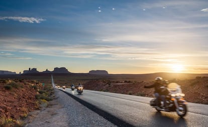 Motoristas curzando por carretera el parque tribal de los indios Navajo, con Monument Valley (Utah) al fondo.