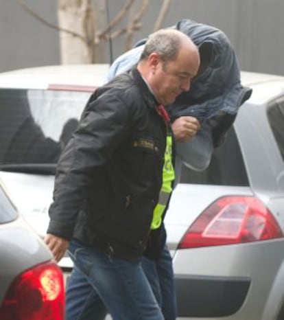 One of the arrested brothers, his head hidden beneath his jacket, arrives at court.