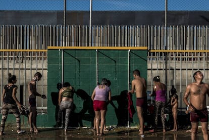 Migrantes se duchan en el albergue Benito Juárez a unos metros del muro fronterizo.