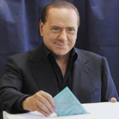 El primer ministro italiano, Silvio Berlusconi, deposita su voto en la urna de un colegio electoral en Milán