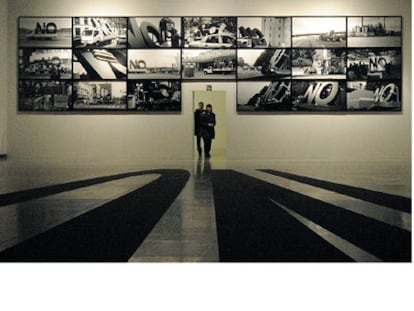 Las  fotografías colocadas en la pared del Artium de Vitoria muestran los diferentes lugares por los que ha ido pasando la escultura del <i>No, global tour</i>, de Santiago Sierra.
Fernando Trueba (a la derecha), con Javier Mariscal.