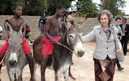 La reina Sofía acaricia uno de los burros que montan unos jóvenes en una aldea del municipio de Namaacha que ha visitado para comprobar los resultados de la cooperación española, durante la última jornada de su visita a Mozambique.