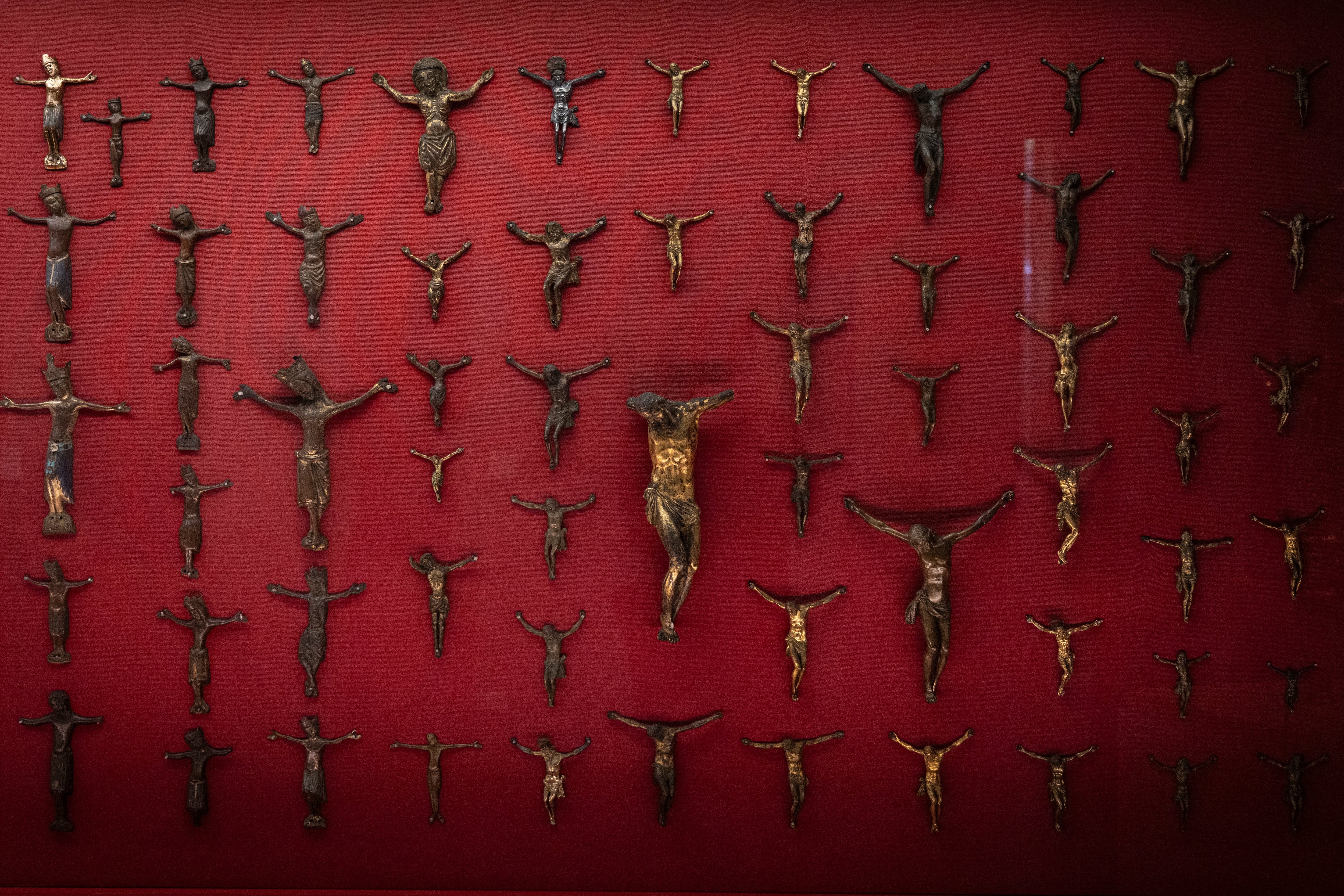 Colección de pequeños crucifijos y esculturas de bronce o madera de Cristo en la cruz expuestos en el museo.