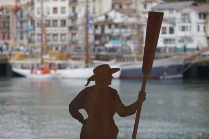 Imagen de una pescadora de bronce con Pasajes San Pedro al fondo.