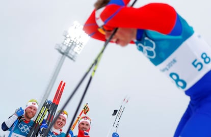 Los noruegos Martin Johnsrud Sundby, Simen Hegstad Krueger y Hans Christer Holund reaccionan cerca del atleta Petr Knop (d) de República Checa durante la prueba de esquí de fondo, el 11 de febrero de 2018.