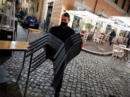 Un camarero recoge las sillas, el viernes, en un restaurante del Trastévere (Roma).