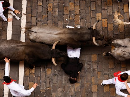 Los toros pasan por encima de un mozo, durante el sexto encierro de San Fermín.