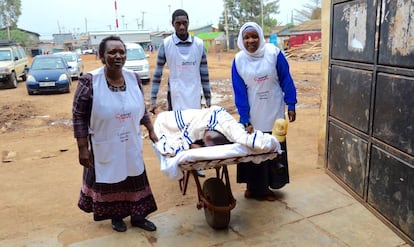 Un par de agentes de salud trasladan a un enfermo en una carretilla transformada en ambulancia hasta el hospital de Amref Salud África en Kibera.