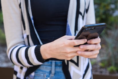 Una mujer envía un mensaje de texto con su teléfono móvil.