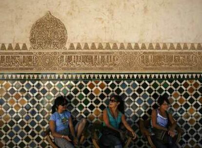 Tres turistas bajo una de las inscripciones de la Alhambra traducidas ahora.