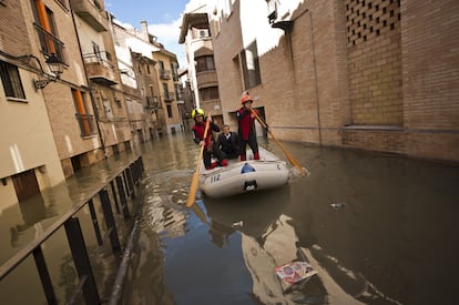 Miembros de Protección Civil ayudan a un vecino en el casco viejo de Tudela, coincidiendo con la máxima crecida del río Ebro, donde se han inundado las calles de la ciudad.