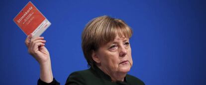 La canciller alemana, Angela Merkel, levanta su tarjeta de votaci&oacute;n durante la jornada del congreso federal de la CDU en Essen 