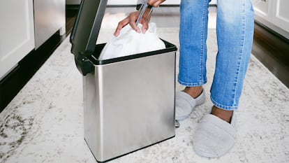 Una persona sacando la bolsa del cubo de basura en su casa.