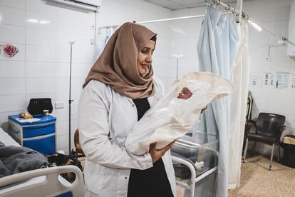 Rahma, supervisora de comadronas, sostiene a un recién nacido llamado Rivan en la maternidad de Al-Amal, en Mosul (Irak).