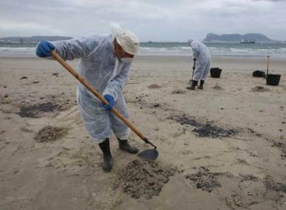 Dos trabajadores del dispositivo desplegado tras el nuevo hundimiento del <i>New Flame </i>recogían ayer restos del vertido registrado en la playa El Rinconcillo de Algeciras.
