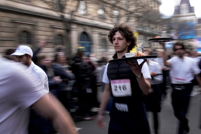 Waiters carry trays with a cup of coffee, a croissant and a glass of water as they take part in a waiter's run through the streets of Paris, Sunday, March 24, 2024.