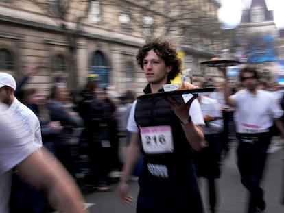 Waiters carry trays with a cup of coffee, a croissant and a glass of water as they take part in a waiter's run through the streets of Paris, Sunday, March 24, 2024.