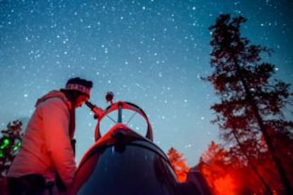 Una mujer mira el cielo a través de un telescopio en el parque nacional de Brecon Beacons.