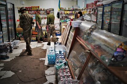 Anastasia Bolous attends to several soldiers in the store that she runs in Orikhiv.