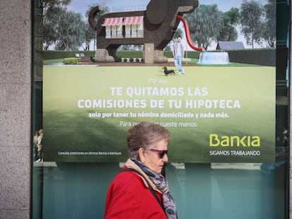 Una mujer pasa ante cartel que publicita hipotecas en una sucursal bancaria. 