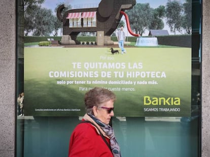 Una mujer pasa ante cartel que publicita hipotecas en una sucursal bancaria. 