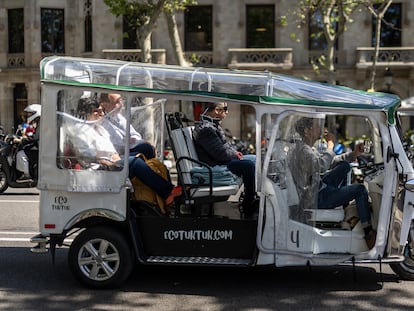 Un grupo de turistas viajan a bordo de un tuk tuk con guía en la plaza de  Catalunya de Barcelona.