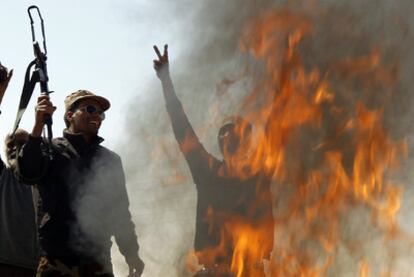 Un grupo de rebeldes junto a una hoguera en la que queman ropa de soldados de Gadafi en la carretera Bengasi-Ajdabiya.