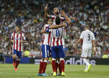 Arda Turan del Atlético Madrid celebra un gol contra el Real Madrid con compañeros Tiago y Raul García.