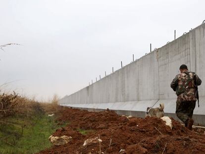 Un combatiente kurdo camina la semana pasada cerca del muro de la frontera turco-siria.