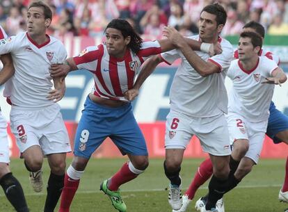 Falcao, entre Navarro y Spahic, en el Atlético-Sevilla de la pasada Liga