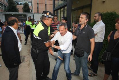 Un policía local forcejea con el líder de PxC, Josep Anglada, a las puertas del Ayuntamiento de Salt durante el pleno de ayer.