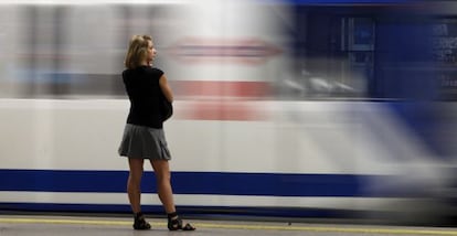 Una mujer observa un tren de metro al entrar en la estaci&oacute;n.