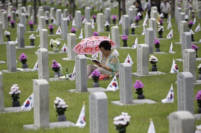 Una mujer lee ante la tumba de su hermano en el Cementerio Nacional de Seúl, la víspera del Día de los Caídos en Corea del Sur.