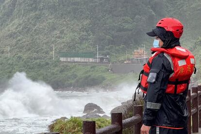 A coast guard officer watches as waves crash on the shore ahead of typhoon Khanun