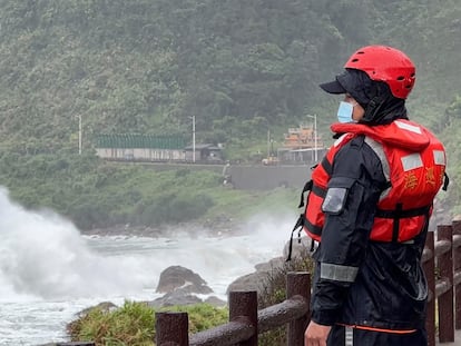 A coast guard officer watches as waves crash on the shore ahead of typhoon Khanun in the port city of Keelung near Taipei in northern Taiwan on Thursday, Aug. 3, 2023.
