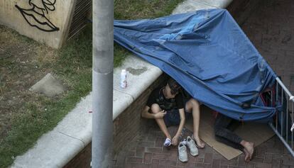 Dos jóvenes migrantes descansan en los jardines exteriores del Monasterio Sant Pau del Camp.