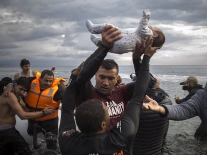Voluntarios ayudan al desembarco de inmigrantes, entre ellos un beb&eacute;, en la isla griega de Lesbos.