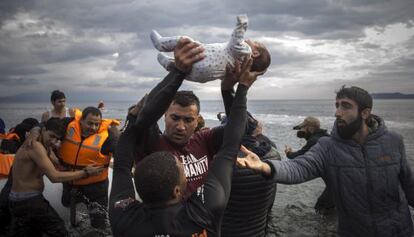 Voluntarios ayudan al desembarco de inmigrantes, entre ellos un beb&eacute;, en la isla griega de Lesbos.