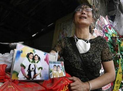 Una mujer muestra las fotos de sus hijas gemelas, muertas en Dujiangyan al derrumbarse su colegio.