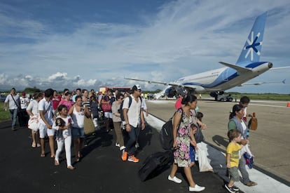 Varios turistas esperaban su vuelo a la ciudad de México, a pie en el aeropuerto de Acapulco, estado de Guerrero inundado por las fuertes lluvias que han afectado el país.