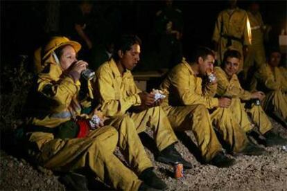 En la imagen, miembros del retén hacen un alto en las tareas de extinción del fuego, que ha calcinado 13.000 hectáreas.