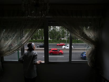 Una mujer observa el tráfico desde su casa en el barrio de Batán de Madrid.